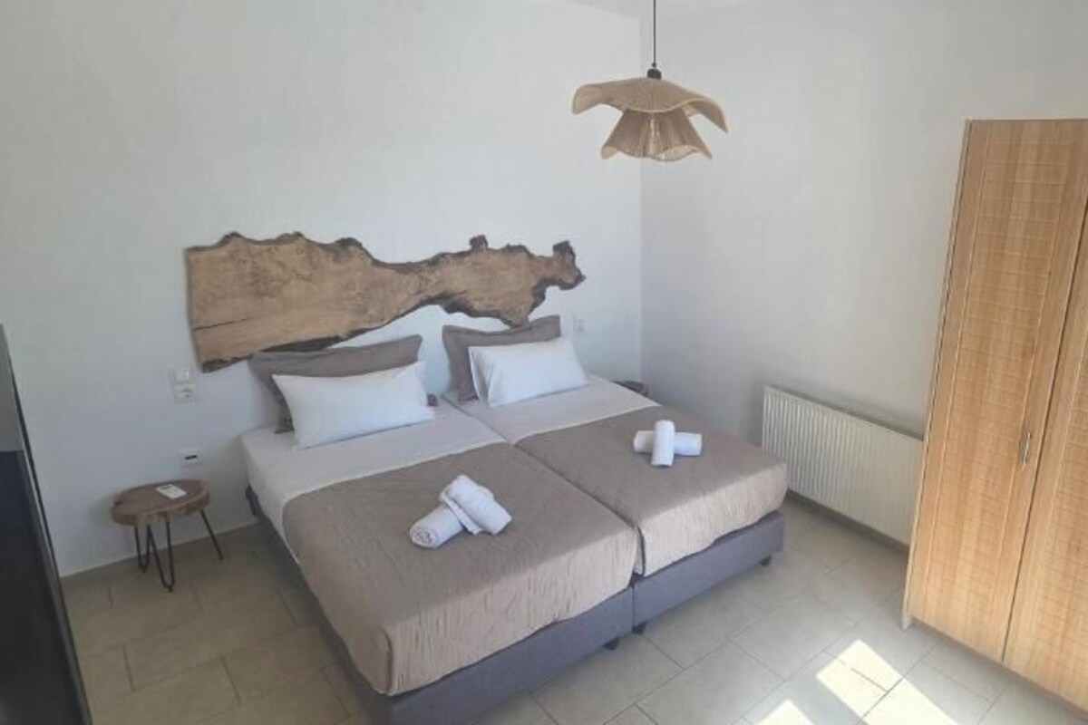 Ein Schlafzimmer mit Bett, Nachttischen, einem Holz-Kopfteil, einem Kleiderschrank und einer Hängeleuchte.