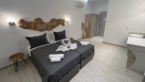 Een moderne hotelkamer met een groot bed, een rond houten bijzettafeltje, een wandlamp en een groot decoratief object boven het bed.