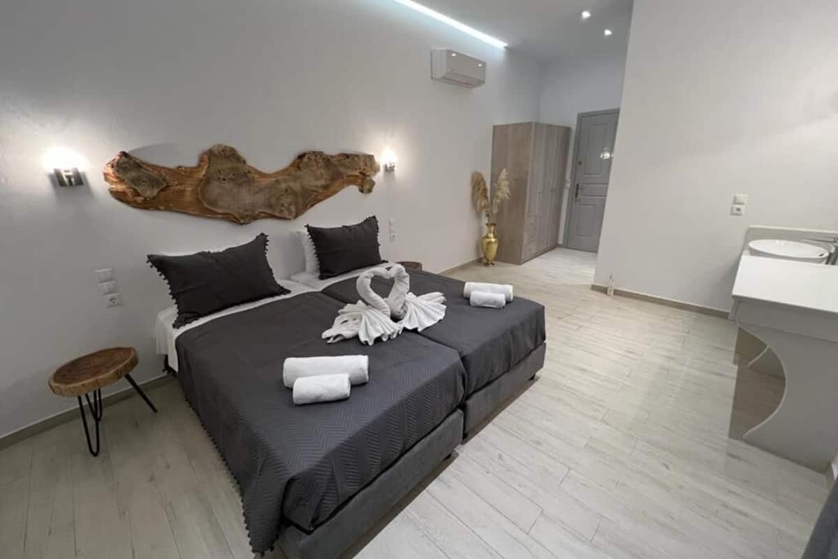 Une chambre d’hôtel moderne avec un grand lit, une petite table d’appoint ronde en bois, un luminaire fixé au mur et un grand élément décoratif au-dessus du lit.