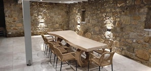 A stone-walled room with a long wooden table and wicker chairs. - Mykonian Tramonti Villas (Mykonos)