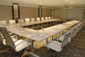 Une salle de conférence équipée d’une longue table, de chaises et d’un écran de projection.