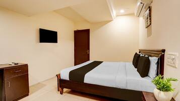 A bedroom with a bed, a dresser, a potted plant, and an air conditioning unit.