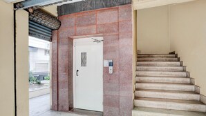A staircase leading to an elevator, with a door and a control panel on the wall.