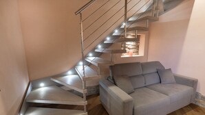 Un intérieur moderne avec un escalier en colimaçon, un canapé gris et un plancher en bois.