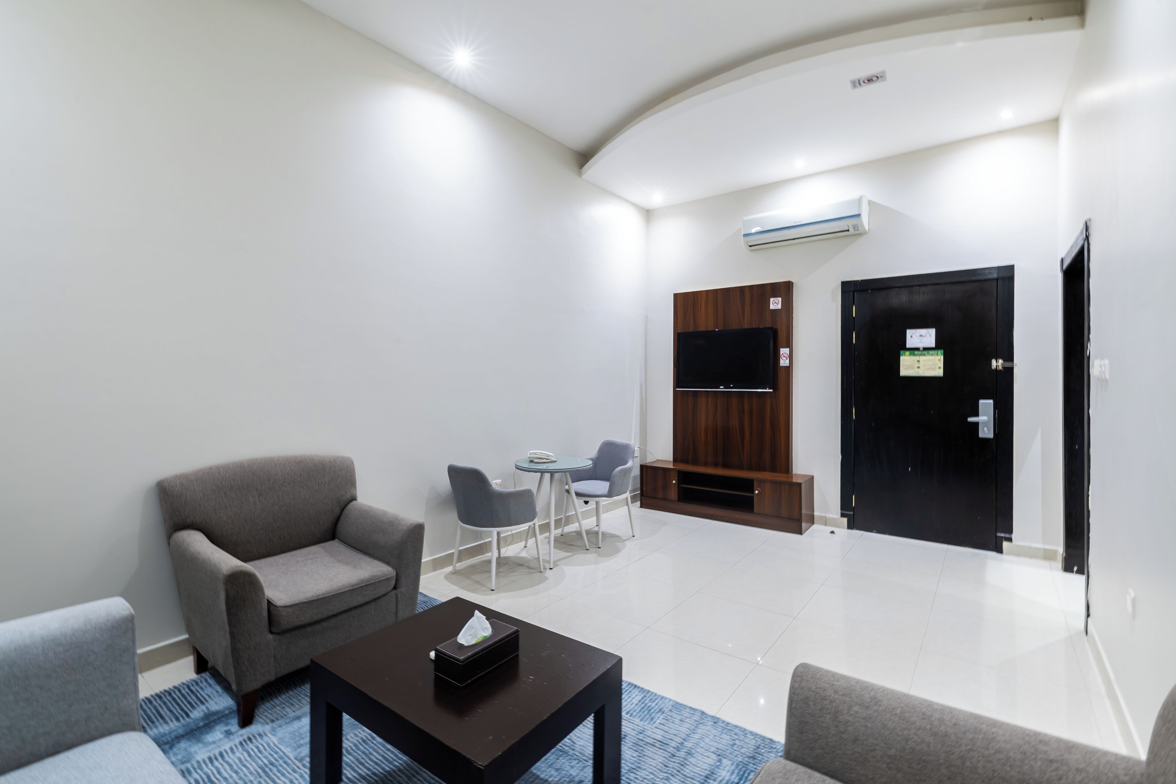 Une chambre d’hôtel moderne équipée d’un canapé, d’une petite table, d’une télévision, d’un bureau et d’une armoire.