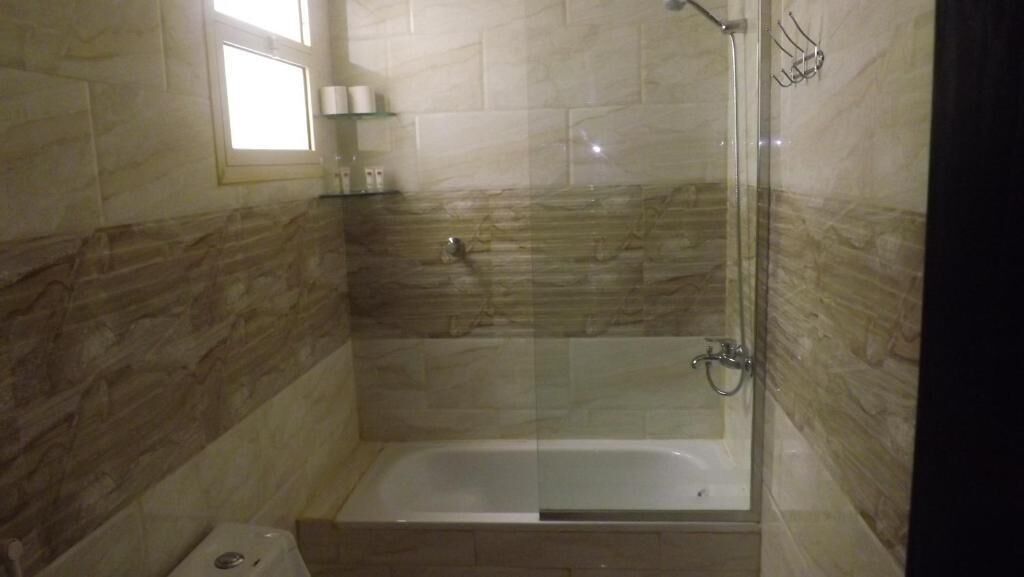 A shower area with a glass door, a bathtub, and a window.