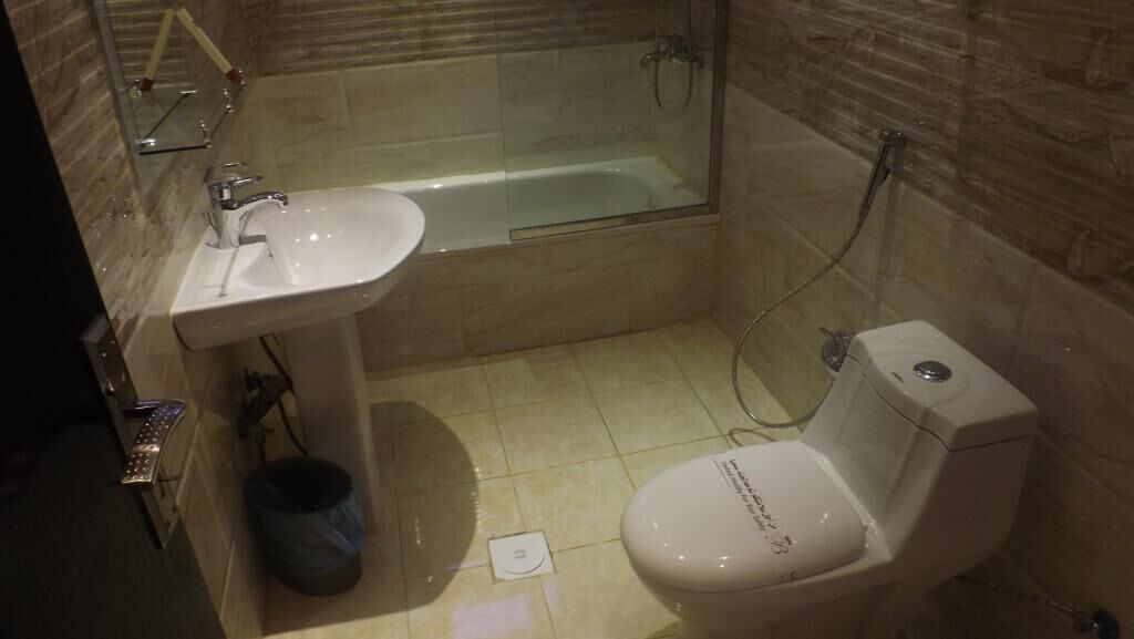 A bathroom with a glass-enclosed shower, a white sink, and a toilet.