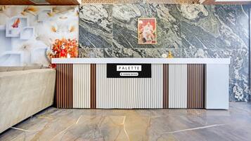 A reception desk with a marble wall behind it, a framed picture, and a sign that reads 'PALETTE Company-Serviced'.