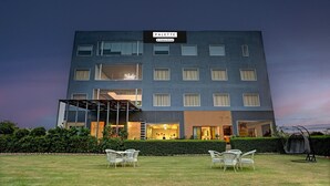 A modern building with a sign reading 'PALETTE' and a covered outdoor seating area with chairs. - Deluxebellazio Suites Hotel & Resort in Bareilly (Bareilly)