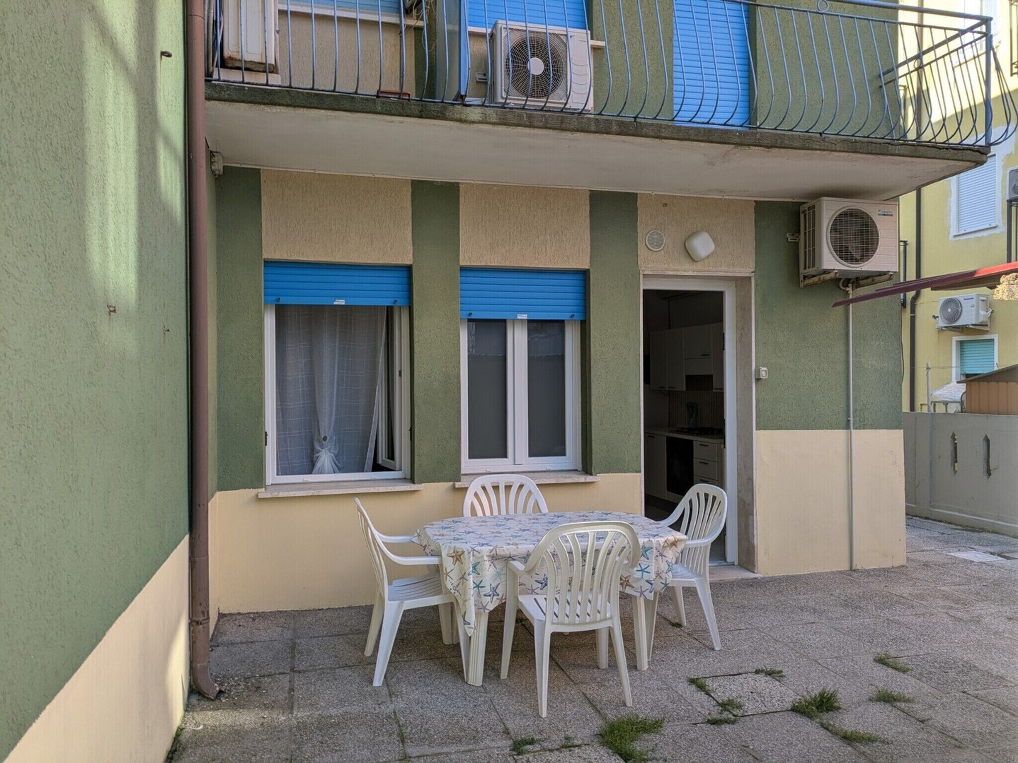 Un bâtiment à deux étages doté d’un balcon, d’une table avec des chaises et d’un appareil de climatisation.