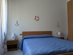 Ein Schlafzimmer mit einem Holzbett, zwei Nachttischen mit Lampen, einer Wanddekoration in Form eines Rettungsboys und einer Anker-Dekoration.