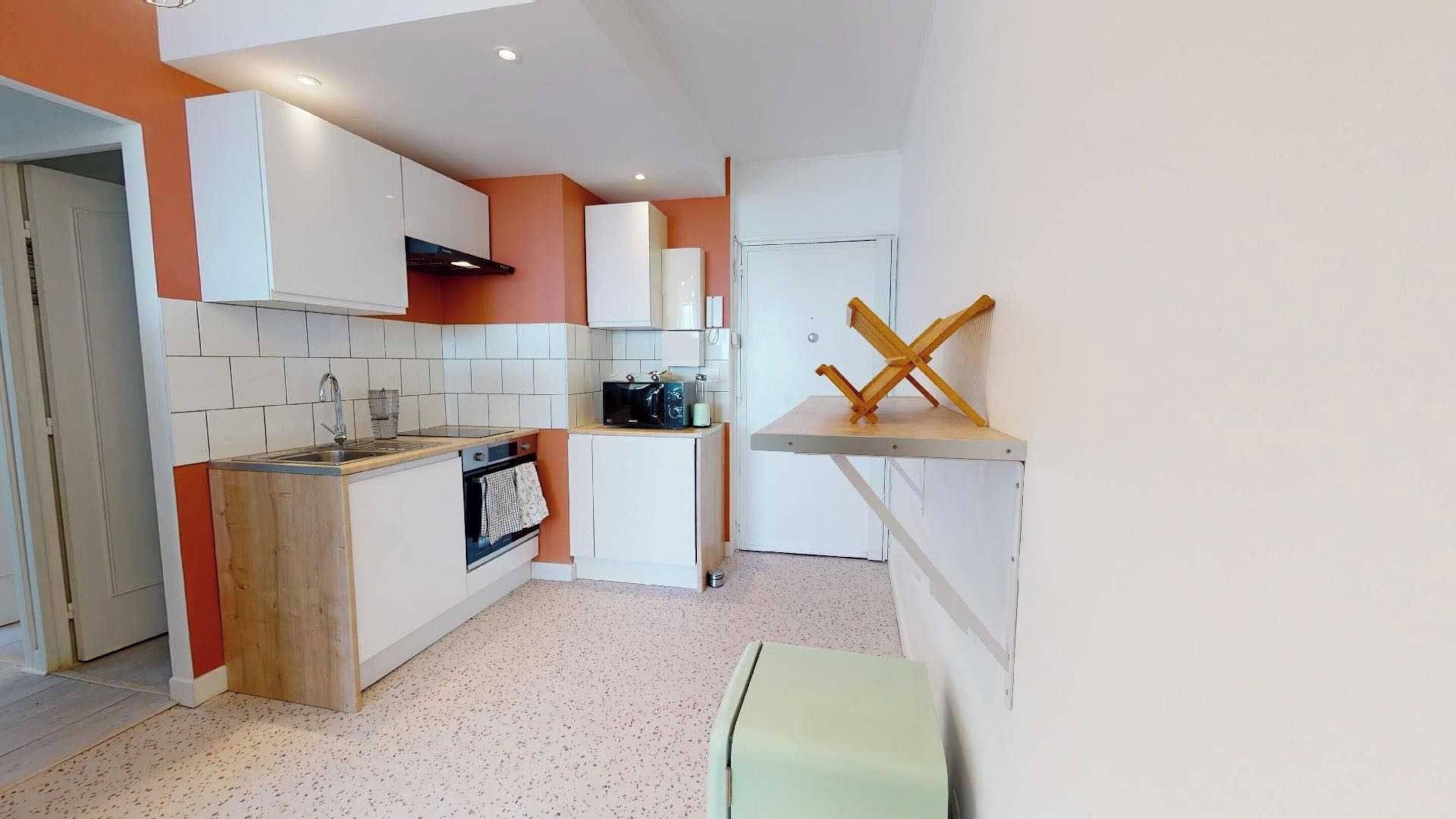 A compact kitchen with white cabinets, a wooden countertop, and a small oven.