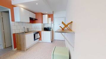 A compact kitchen with white cabinets, a wooden countertop, and a small oven.