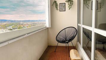 A balcony with a black chair, a wooden bench, and two framed artworks on the wall.