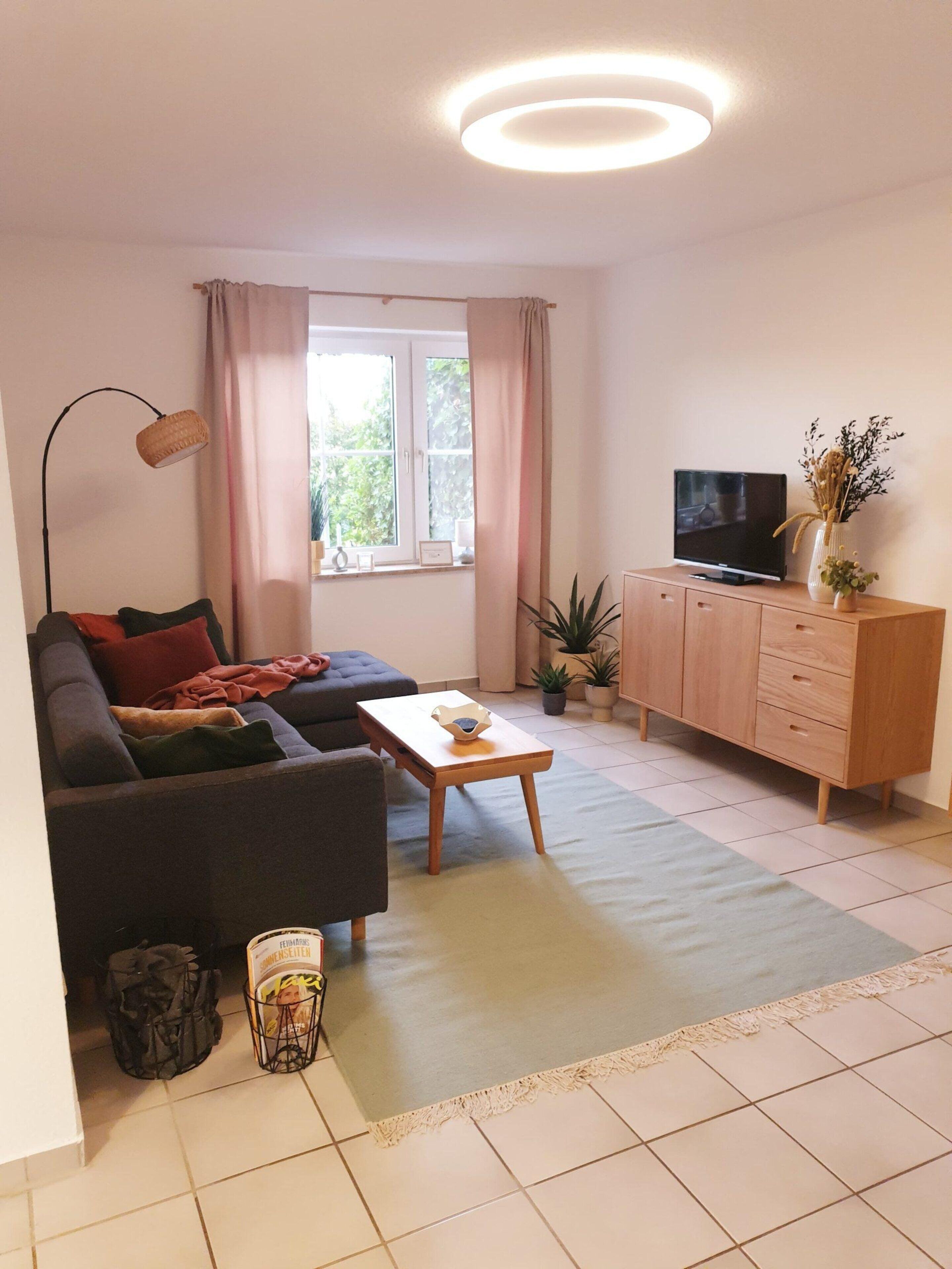 Ein modernes Wohnzimmer mit einer Couch, einem Couchtisch, einem Fernseher und einem Schrank.