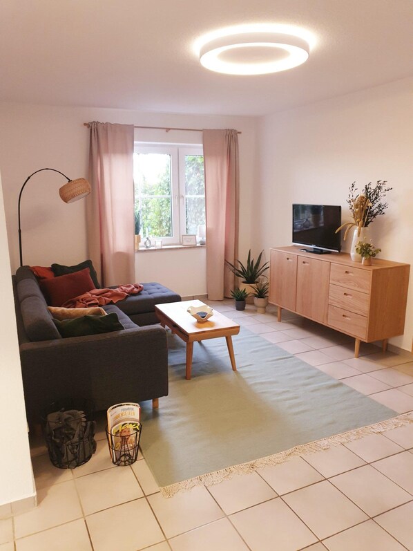 Ett modernt vardagsrum med en soffa, ett soffbord, en tv och ett skåp.