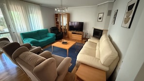 A living room with a sofa, armchair, coffee table, TV, and a fireplace.