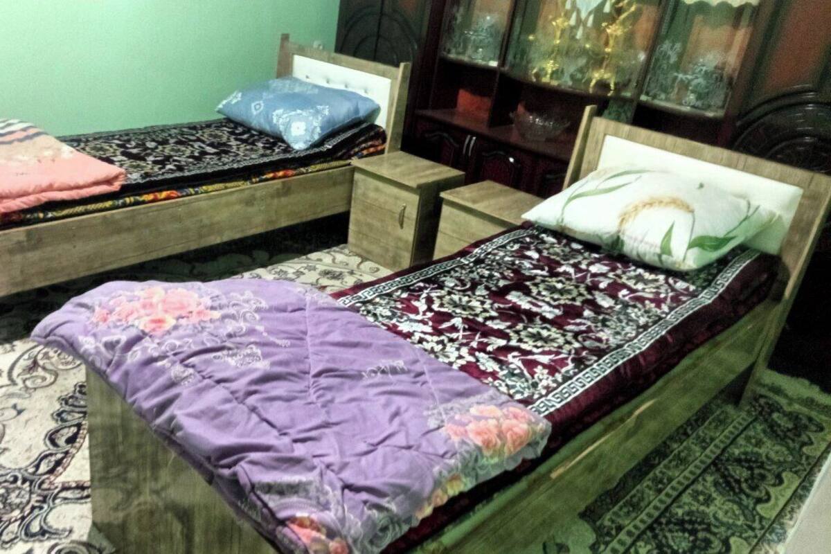 Two wooden beds with headboards, a small wooden nightstand, and a patterned rug.