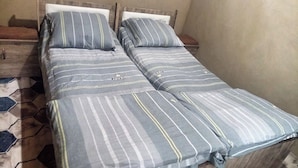 A twin bed with striped bedding, a wooden headboard, and a bedside table with a lamp.