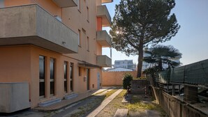 Un edificio residencial con fachada plana, varios balcones y un patio empedrado.