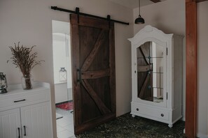 Quarto com porta de celeiro deslizante, um armário branco com gavetas, um armário com espelho e um lustre.