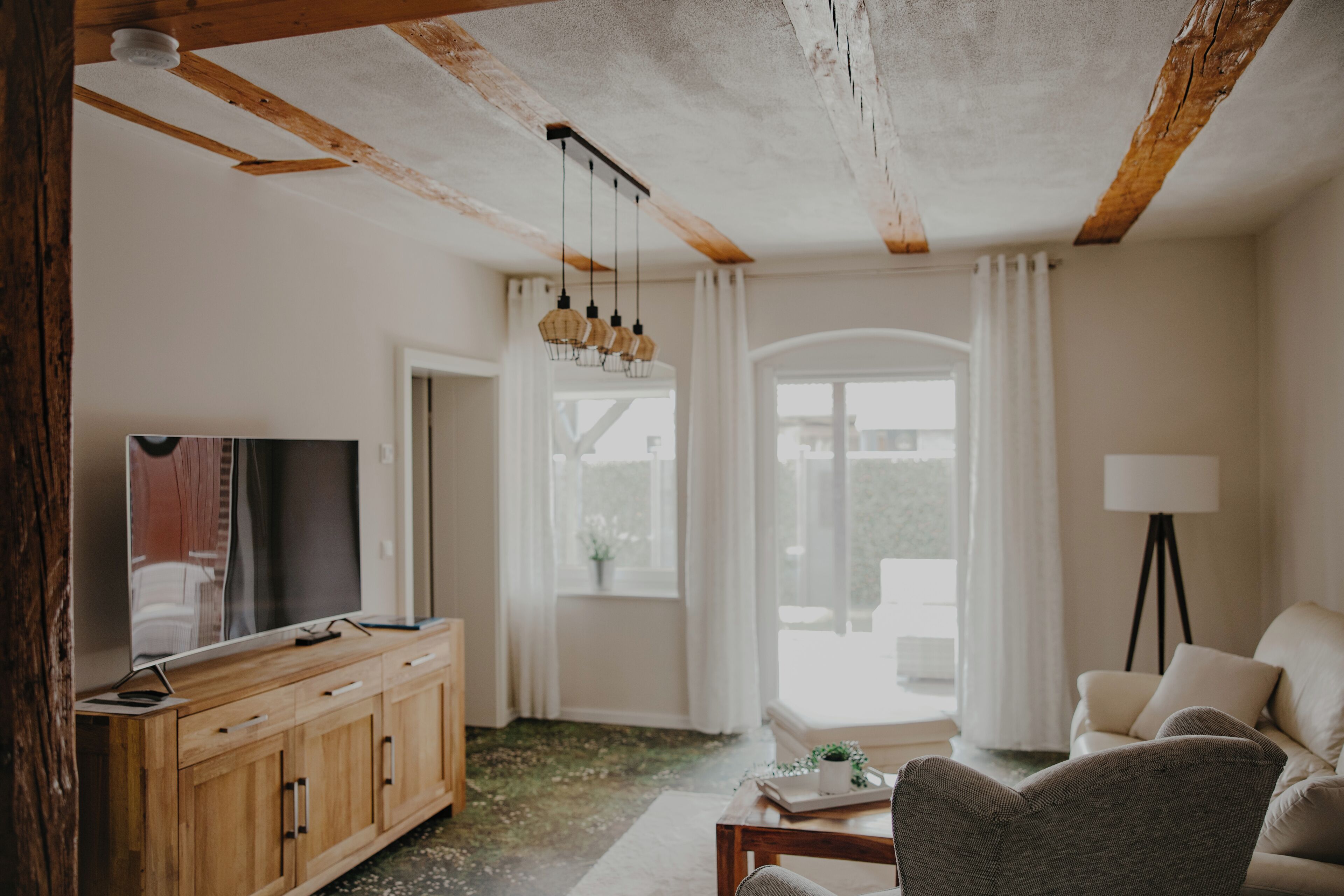 Een woonkamer met een houten kast, een televisie, een bank, een salontafel en een lamp.