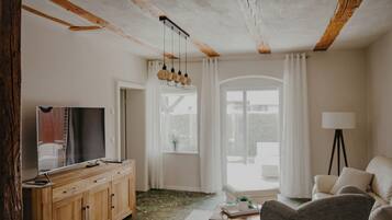 Een woonkamer met een houten kast, een televisie, een bank, een salontafel en een lamp.