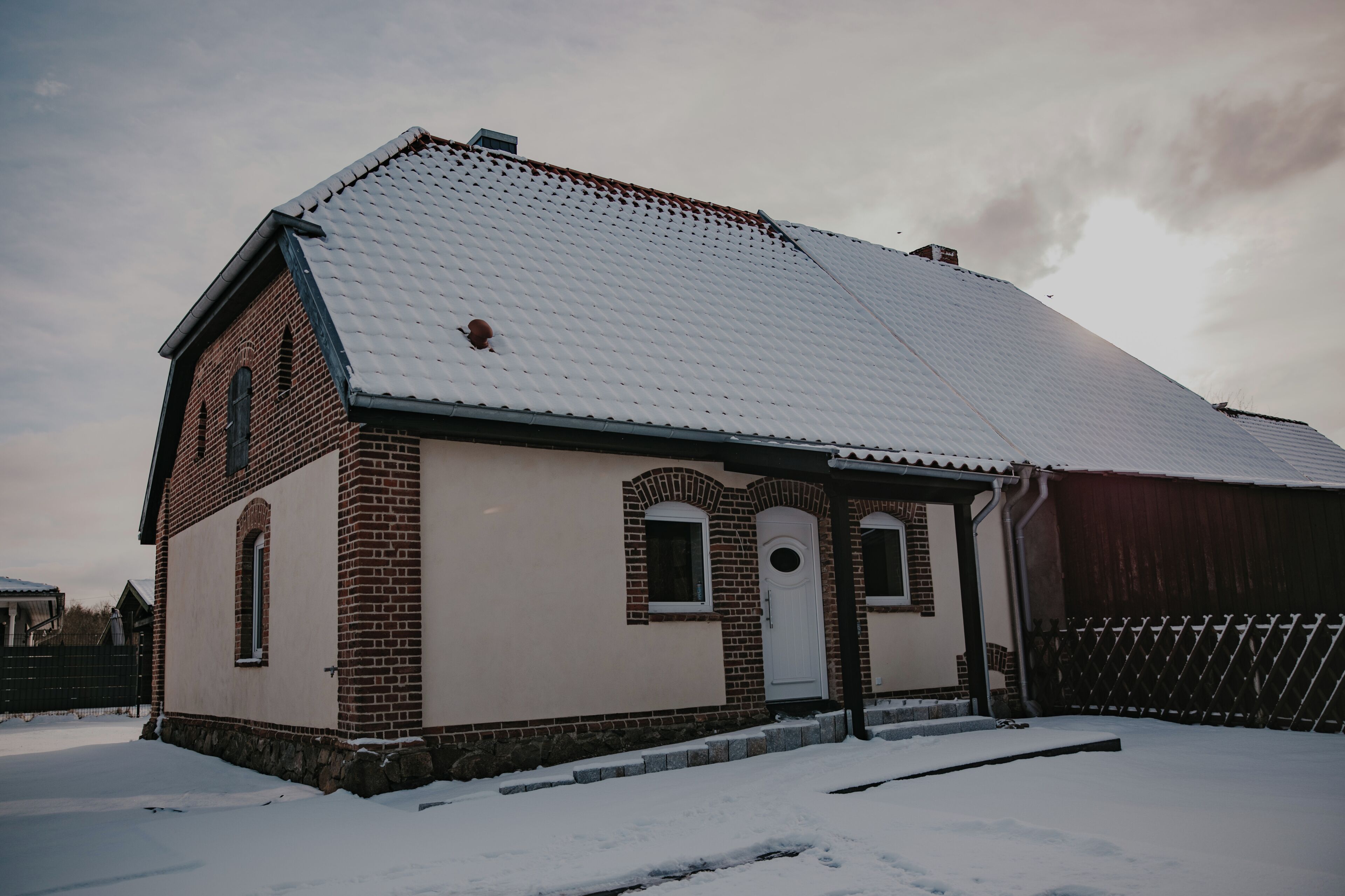 A brick building with a snow-covered roof and a small porch.