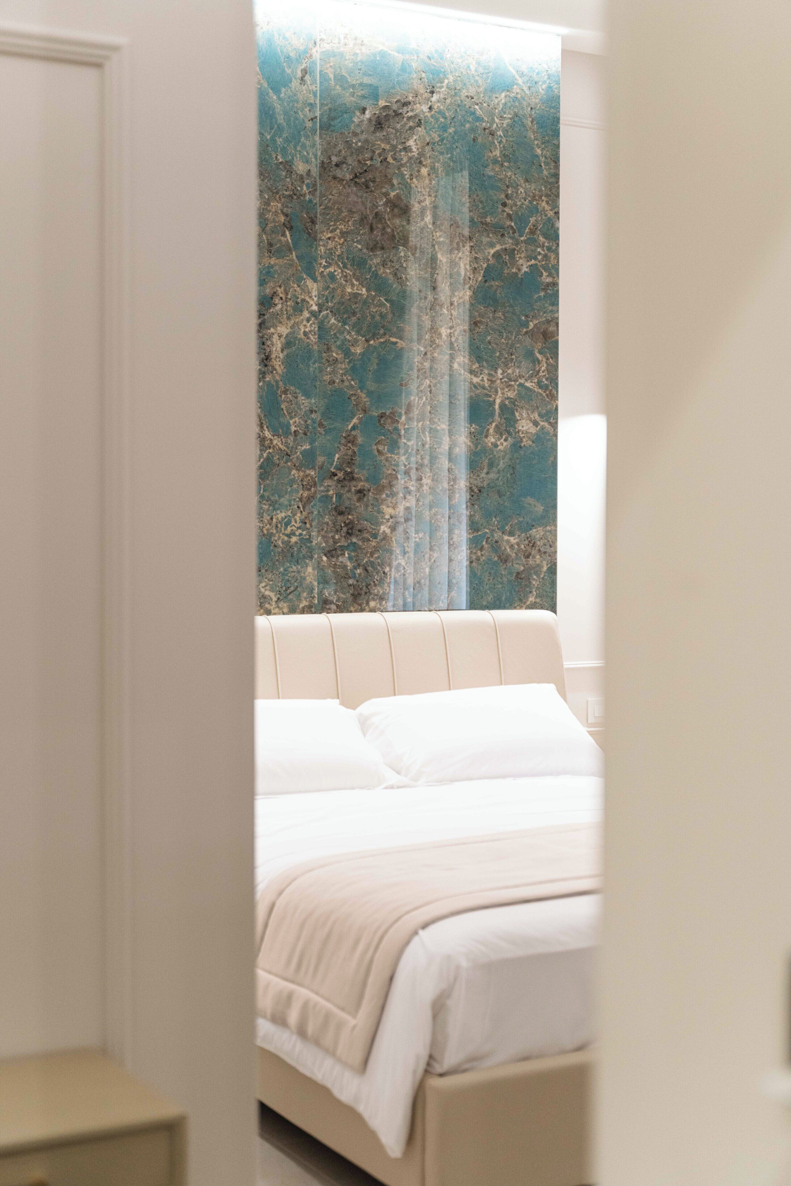 A bedroom with a bed, a nightstand, and a wall with a textured pattern.