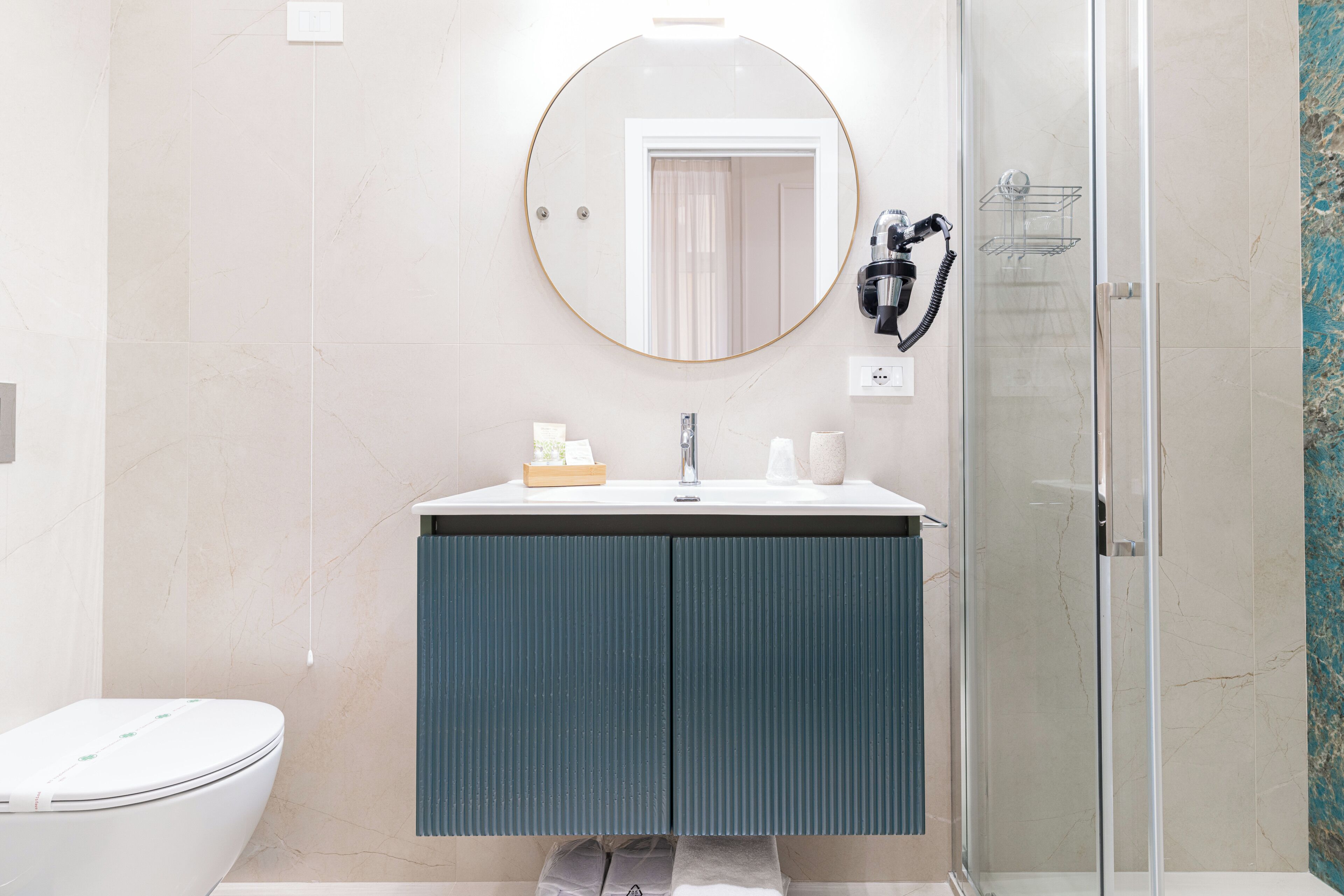 A bathroom with a toilet, a sink with a mirror, and a shower area.