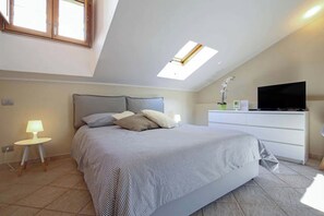 A bedroom with a bed, a desk with a TV, a small table with a lamp, and a skylight. - Modern facility in the heart of Salerno in the central Piazza Portanova (Salerno)