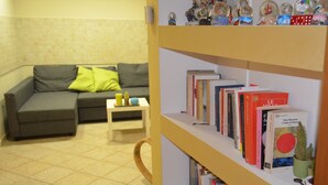 Un soggiorno con un divano grigio, un tavolino con libri e una libreria piena di volumi.