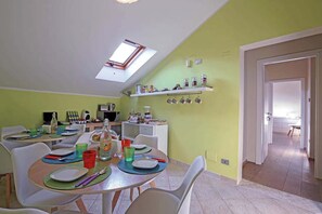 A dining area with a table set for four, a kitchen in the background, and a skylight above. - Modern facility in the heart of Salerno in the central Piazza Portanova (Salerno)