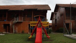 Ein Wohngebäude mit Ziegelaußenwand, einer Treppe, die zu einem Balkon führt, und einem Spielplatz mit einer roten Rutsche.