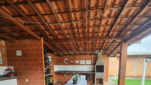 Eine Terrasse im Freien mit gefliestem Boden, einem Tisch mit Stühlen, einer Backsteinmauer und einem Grill.