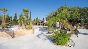 Een resortgebied met palmbomen, een zwembad en terraszitplaatsen.