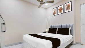 A modern bedroom with a bed, a ceiling fan, a nightstand, a lamp, and framed artwork on the wall. - Suite Marquis Street BK International (Kolkata)