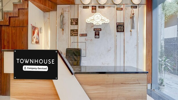 A reception desk with a sign reading 'TOWNHOUSE Company-Serviced.' - Deluxe With Twin Bedram Talai Crossway (Amritsar)