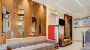 A modern lobby with a sofa, a red refrigerator, and a television on the wall. - Deluxe With Twin Bedram Talai Crossway (Amritsar)