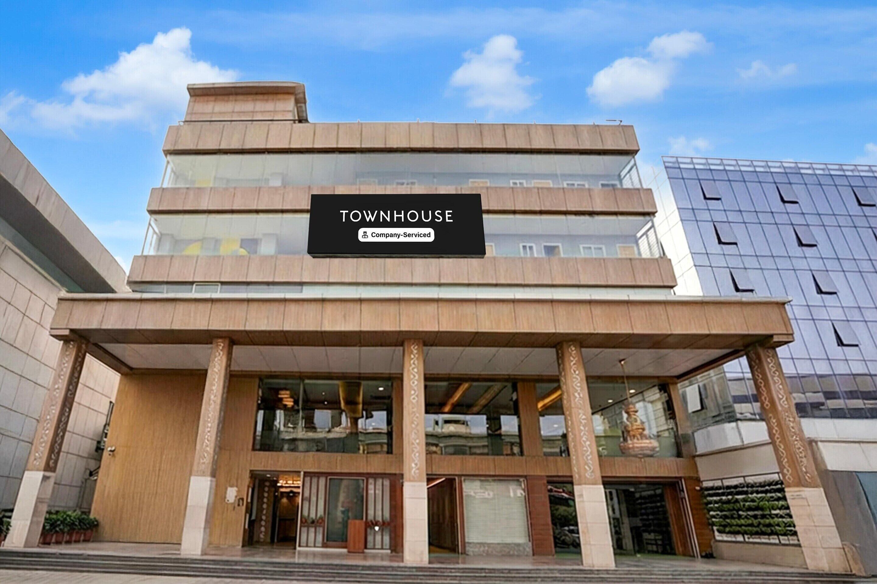 En byggnad med flera våningar, med en skylt som visar texten ”TOWNHOUSE” och ”Företagsservice”.