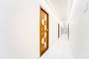 Un pasillo largo e iluminado, con paredes blancas y puertas de madera.