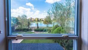 A window with a view of a lake, trees, and a grassy area. - 3-Bdrm, 2.5-Bth WaterFront View Home (Katy)