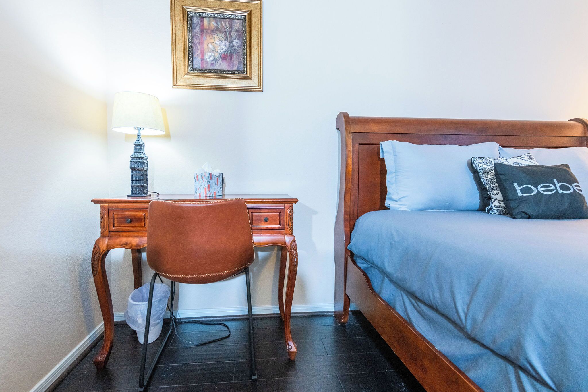 Un dormitorio con una cama de madera, un escritorio con lámpara y una silla.