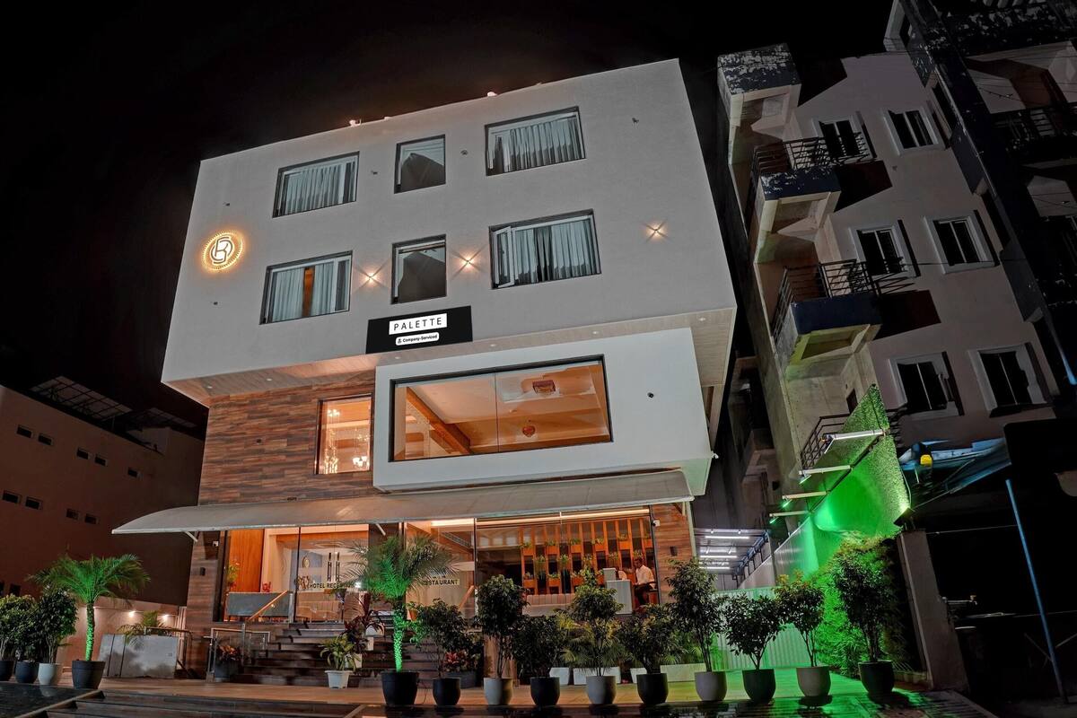 Un hotel de varios pisos con diseño moderno, que destaca un letrero grande para el restaurante 'PALETTE' en la planta baja.