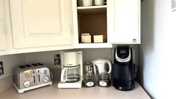 A kitchen with a toaster, a coffee maker, a kettle, and jars on the counter.