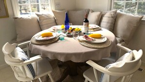 Une table à manger avec des assiettes, des couverts et une bouteille, entourée de chaises blanches.