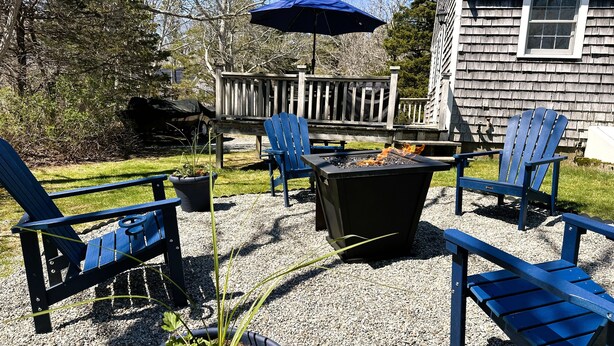 Une terrasse avec des fauteuils Adirondack, un foyer et une plateforme en bois.