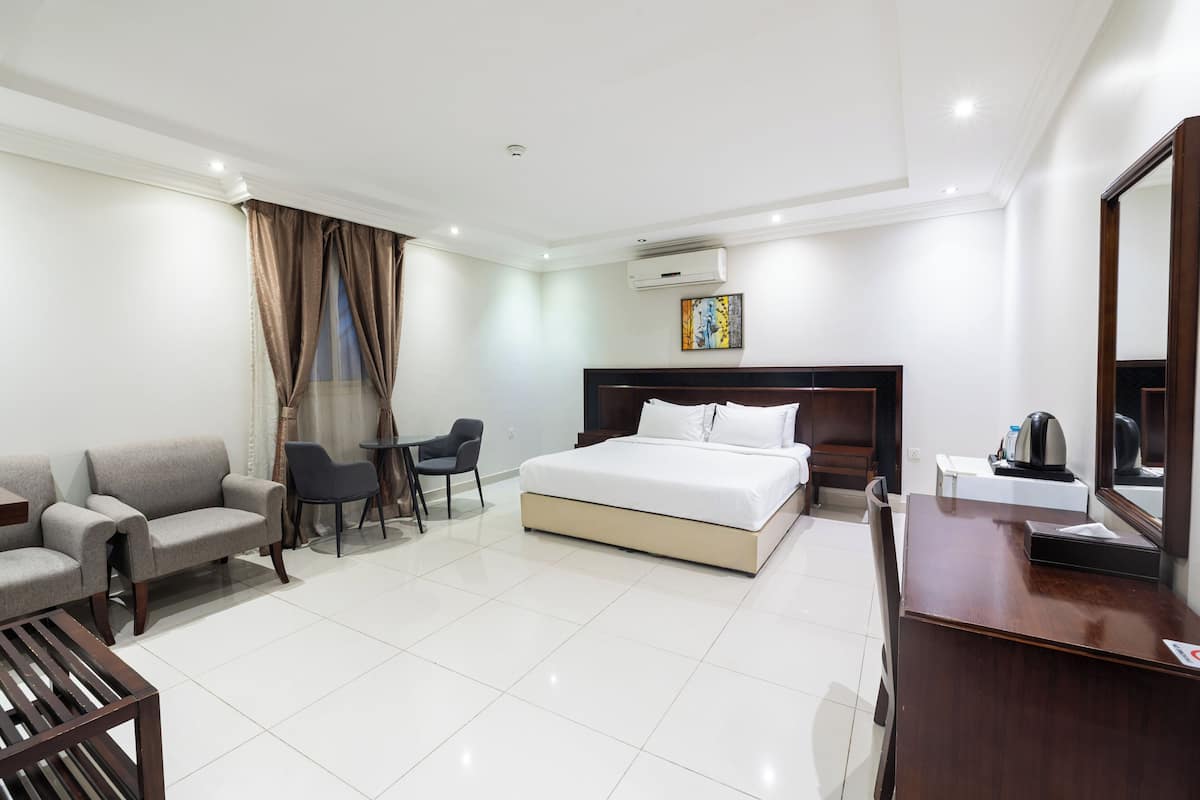 Quarto de hotel com cama, escrivaninha, cadeira, sofá e ar condicionado.