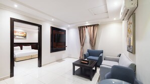Habitación de hotel con cama, televisión montada en la pared, sofá, mesa de centro y un cuadro.