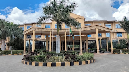 A multi-story building with a central courtyard, palm trees, and a flagpole.. The Royal Ambassador Hotel